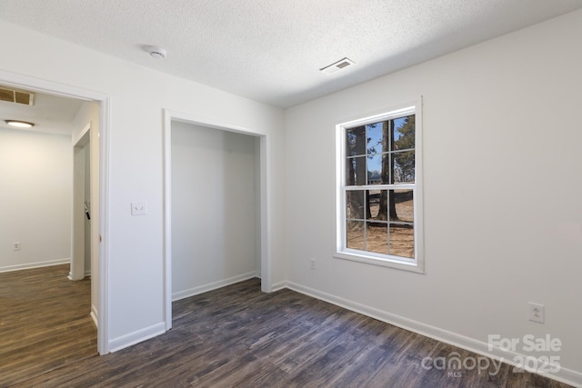 unfurnished bedroom featuring dark wood-style floors, a closet, visible vents, and baseboards