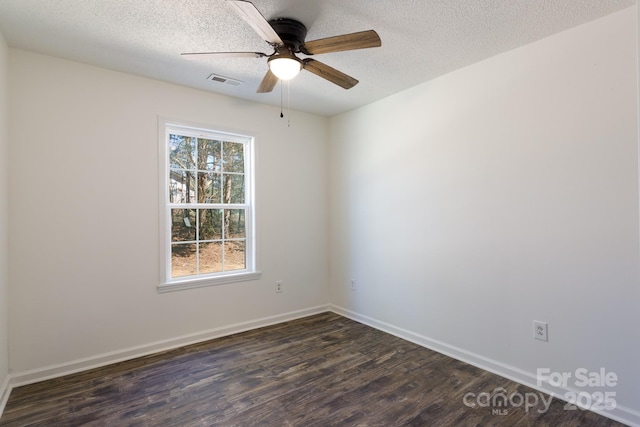 spare room featuring baseboards, visible vents, a ceiling fan, dark wood-style floors, and a textured ceiling