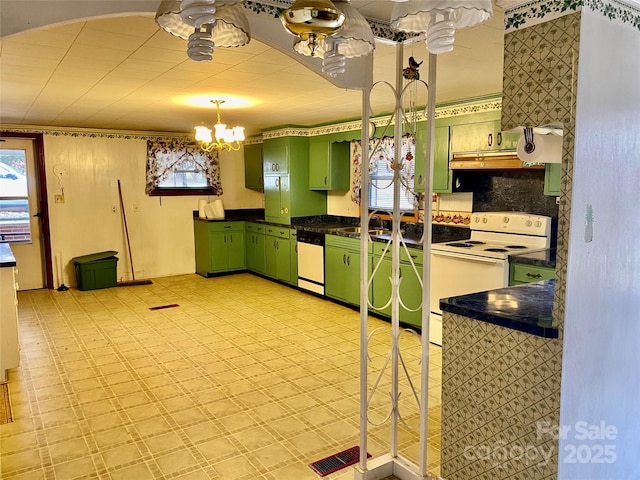 kitchen with under cabinet range hood, white appliances, green cabinets, light floors, and dark countertops