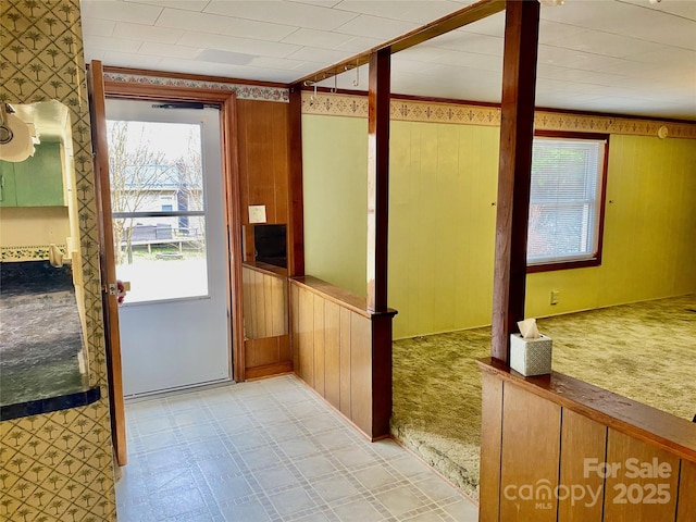 doorway with light floors and wood walls