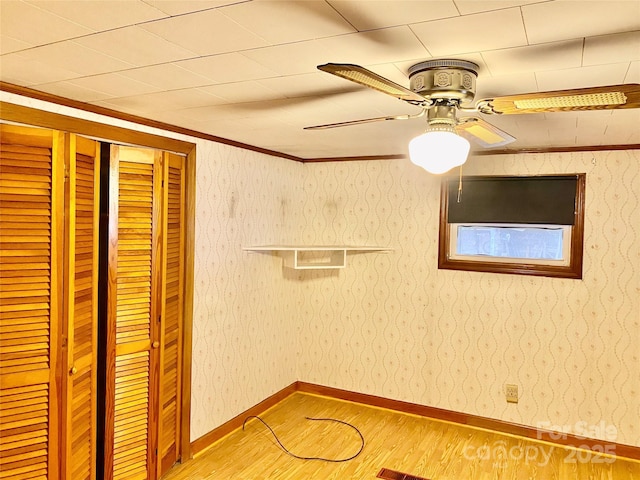 interior space featuring baseboards, ceiling fan, wood finished floors, and wallpapered walls