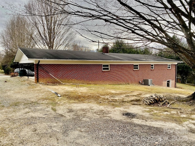 view of property exterior with driveway, brick siding, and central AC unit