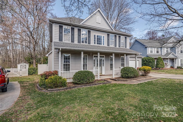 view of front of property with a porch, a garage, a shingled roof, fence, and a front yard