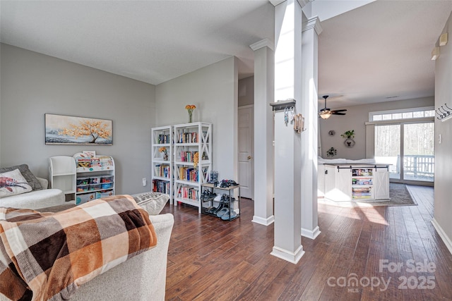 interior space with ornate columns, baseboards, dark wood finished floors, and a ceiling fan