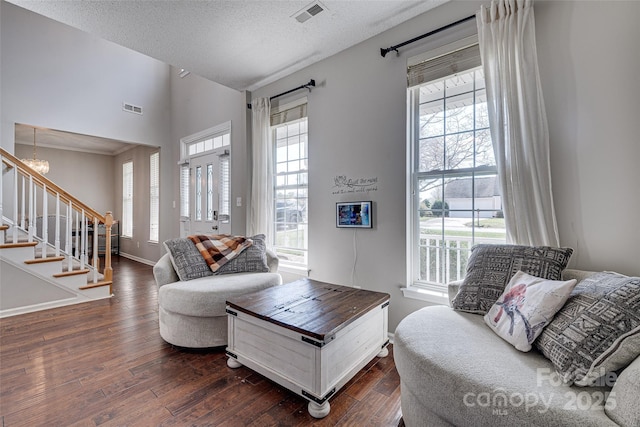 living area with dark wood-type flooring, stairway, and visible vents