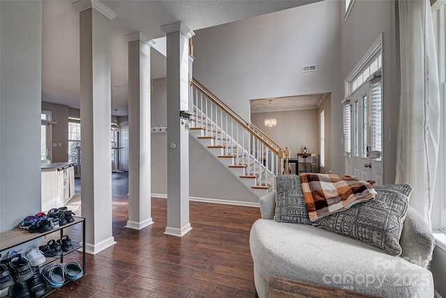 entrance foyer featuring wood finished floors, visible vents, baseboards, stairs, and decorative columns