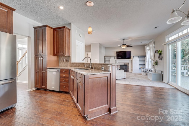 kitchen featuring stainless steel appliances, dark wood-style flooring, a sink, and a peninsula