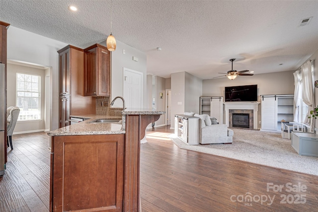 kitchen featuring a ceiling fan, wood-type flooring, a sink, and light stone countertops