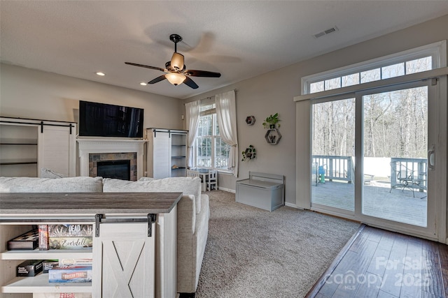 living room featuring baseboards, a barn door, visible vents, and a ceiling fan