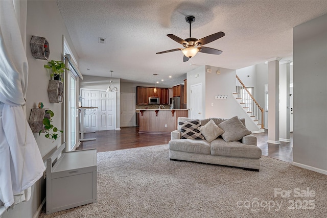 living area with a textured ceiling, stairs, baseboards, and a ceiling fan