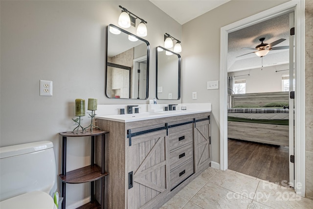 bathroom with double vanity, a ceiling fan, toilet, ensuite bath, and a textured ceiling