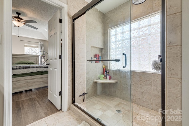 bathroom featuring a ceiling fan, a stall shower, connected bathroom, and a textured ceiling