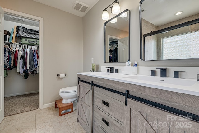 bathroom with double vanity, visible vents, toilet, a spacious closet, and a sink