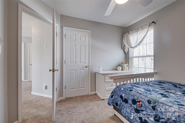 bedroom featuring light carpet, ceiling fan, a textured ceiling, and baseboards