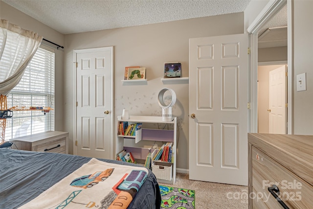 carpeted bedroom featuring a textured ceiling and baseboards