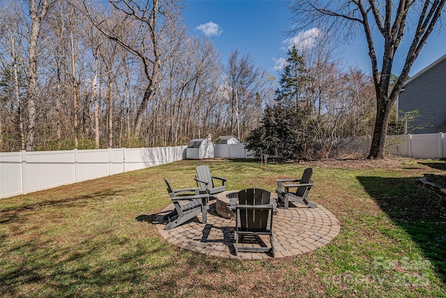 view of yard with a fenced backyard, a fire pit, an outbuilding, and a patio