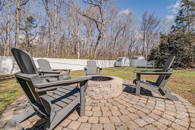 view of patio with an outdoor fire pit, a fenced backyard, an outbuilding, and a shed