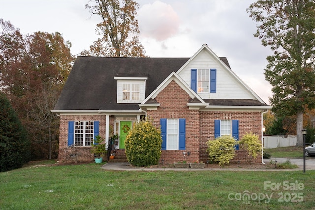 view of front facade with a front yard, fence, and brick siding