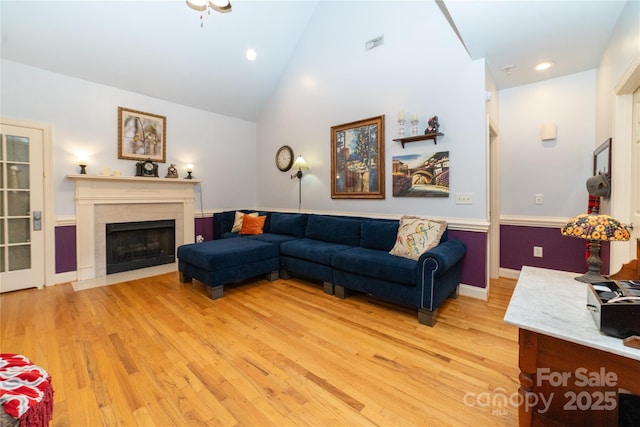 living room with visible vents, a fireplace with flush hearth, recessed lighting, light wood-style flooring, and high vaulted ceiling