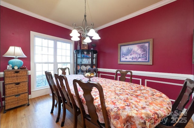 dining room with a notable chandelier, wood finished floors, and ornamental molding