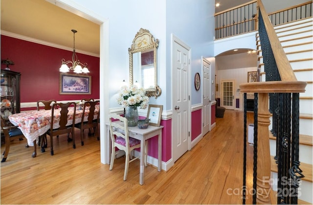 entrance foyer featuring wood finished floors, arched walkways, stairs, crown molding, and a notable chandelier