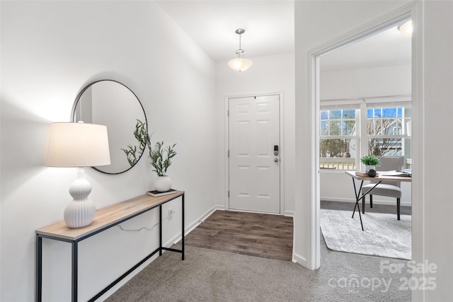 foyer featuring dark carpet and baseboards