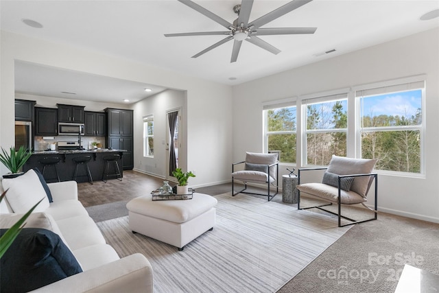 living area with ceiling fan, recessed lighting, visible vents, and baseboards