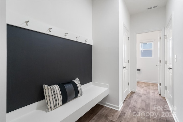 mudroom featuring baseboards, visible vents, and wood finished floors