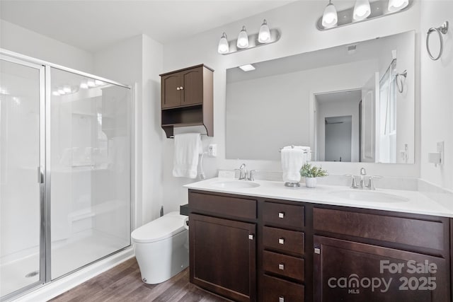 full bath with wood finished floors, a sink, and a shower stall