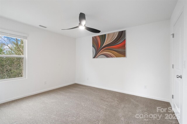 carpeted empty room with a ceiling fan, visible vents, and baseboards