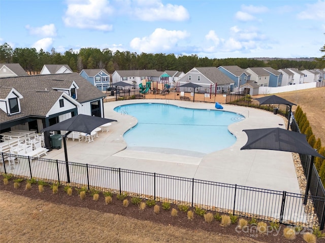 community pool with a patio area, a residential view, and fence