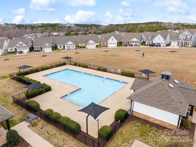 community pool with a patio area, a residential view, and fence