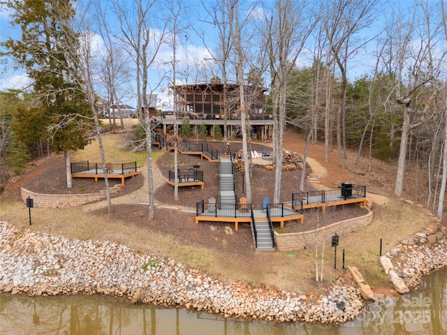 rear view of property featuring a deck with water view and stairway