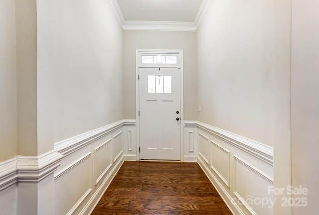 doorway with ornamental molding, dark wood-style flooring, wainscoting, and a decorative wall