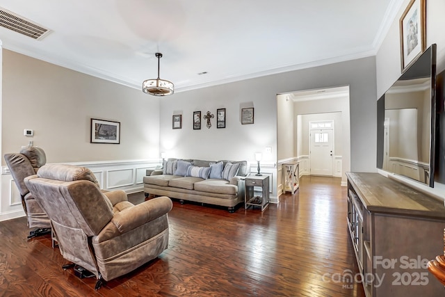 living room featuring dark wood-type flooring, wainscoting, visible vents, and crown molding