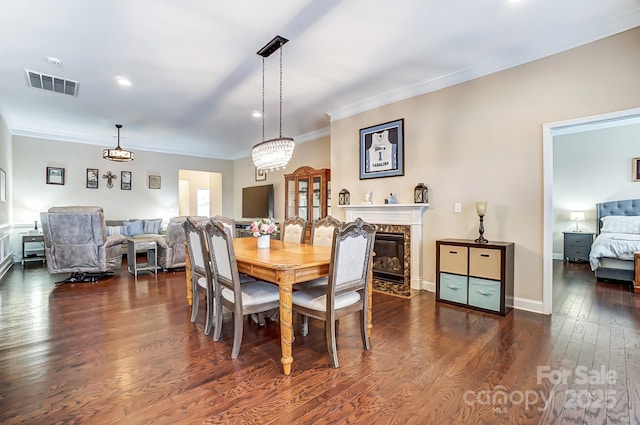 dining room with visible vents, baseboards, a high end fireplace, dark wood finished floors, and crown molding