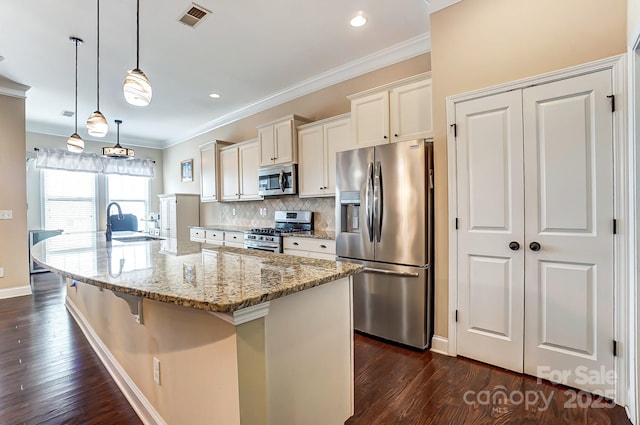 kitchen with crown molding, a large island, stainless steel appliances, visible vents, and backsplash