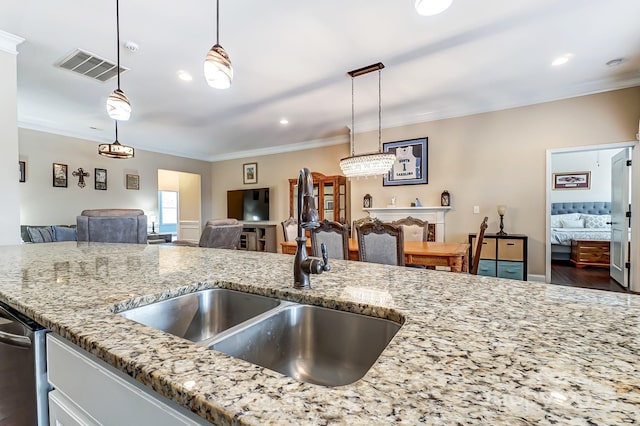 kitchen with a sink, visible vents, open floor plan, ornamental molding, and light stone countertops