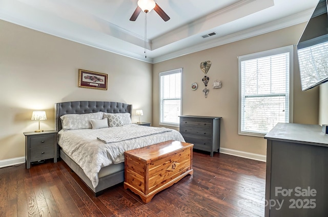 bedroom featuring dark wood-style floors, a tray ceiling, crown molding, visible vents, and baseboards