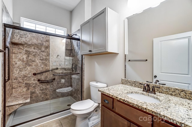 full bath with a stall shower, tile patterned flooring, vanity, and toilet