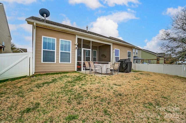 back of property with a patio, a sunroom, a fenced backyard, a gate, and a yard