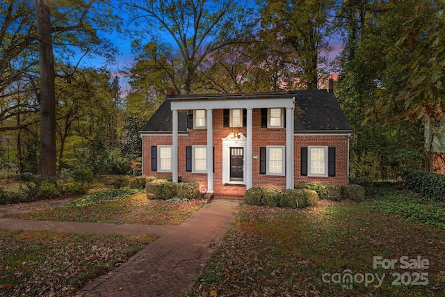 view of front of property featuring roof with shingles, brick siding, and a chimney