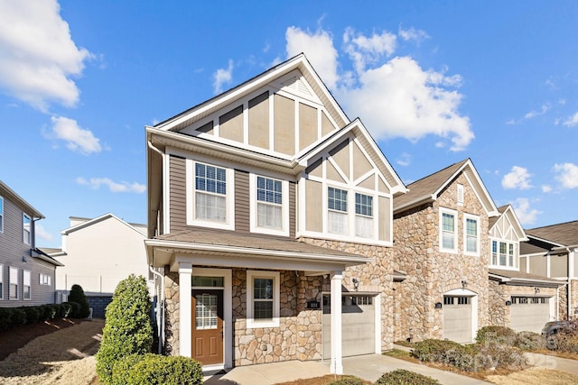 english style home with covered porch, concrete driveway, and an attached garage