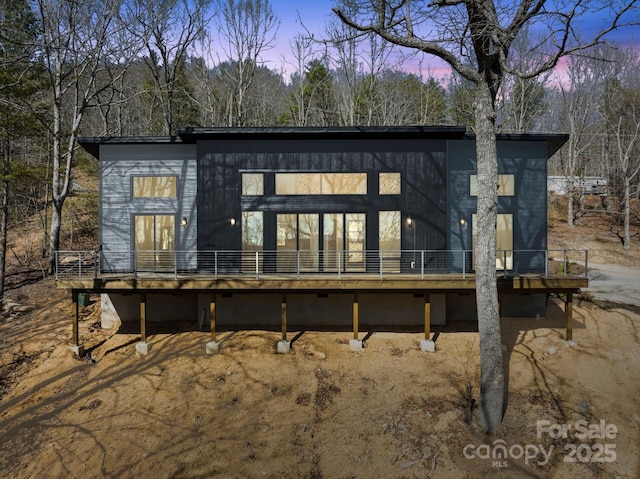 back of house at dusk featuring a wooden deck