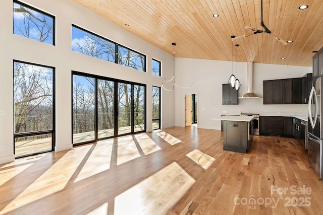 kitchen featuring wooden ceiling, stainless steel appliances, a kitchen island, open floor plan, and wall chimney exhaust hood