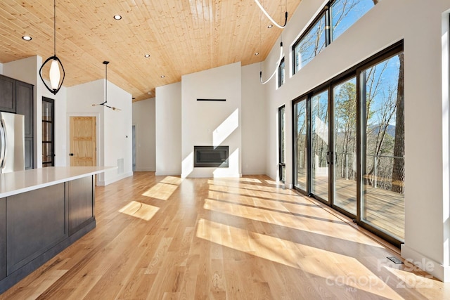 interior space featuring pendant lighting, light countertops, a towering ceiling, wood ceiling, and light wood-type flooring