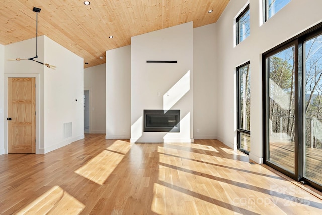 interior space with high vaulted ceiling, wooden ceiling, recessed lighting, wood finished floors, and a glass covered fireplace