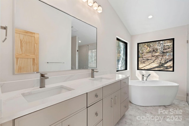 full bathroom with lofted ceiling, a soaking tub, double vanity, and a sink