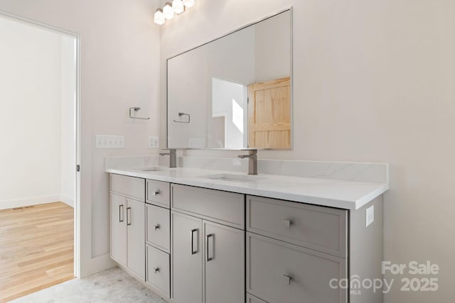 bathroom with double vanity, baseboards, and a sink