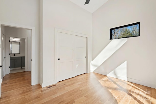 bedroom featuring high vaulted ceiling, visible vents, light wood-style flooring, and baseboards